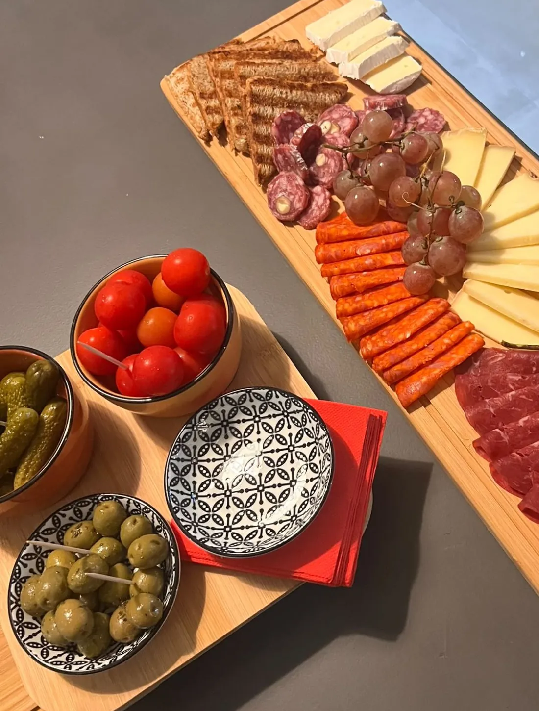 Une planche de charcuterie, fromages et raisin à partager